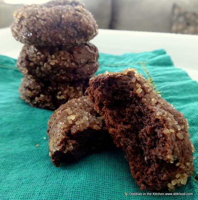 A stack of Mexican Chocolate Cookies on a turquoise napkin with a cookie broken in half to show a fudgy texture. 