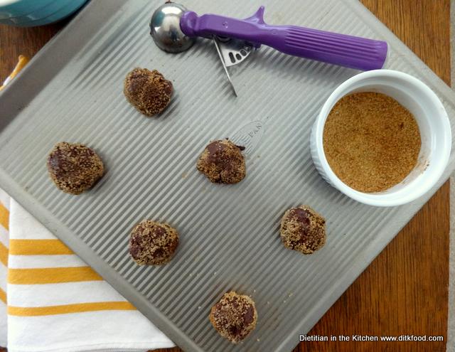 Scooped out Mexican Chocolate Cookies on a baking sheet with a dough scoop and bowl of spiced dipping sugar on the side. 