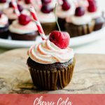 A close-up shot of a chocolate cupcake topped with red striped frosting, a cherry, and a red striped paper straw.