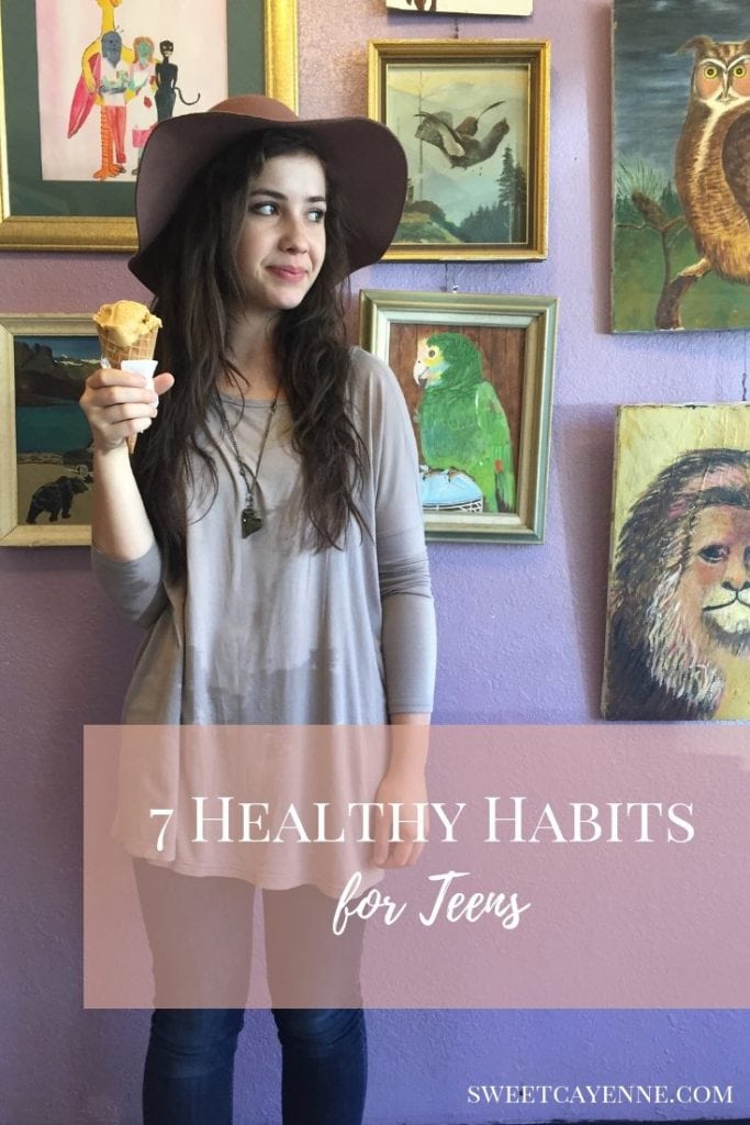 A teen girl standing in from of an art gallery wall and holding an ice cream cone. 