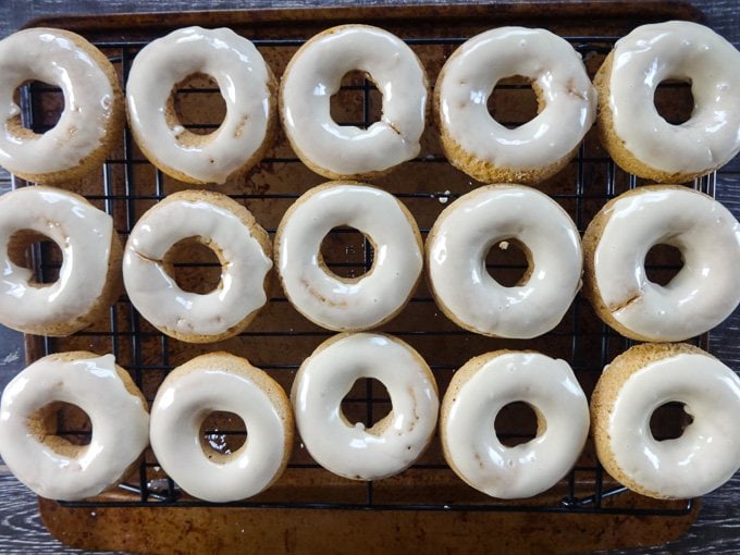 Rows of glazed baked apple cider donuts on a wire cooling rack. 