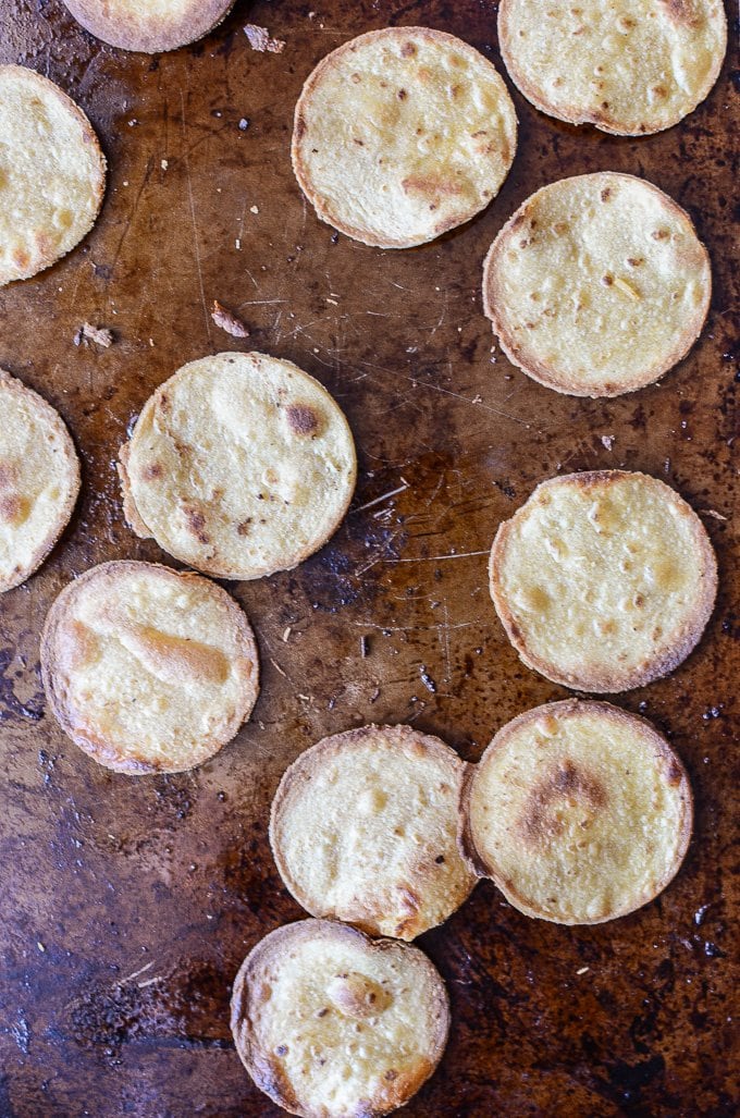 Mini crispy tostada rounds on a baking sheet. 