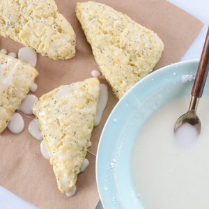 Overhead view of Meyer Lemon Poppyseed Scones with a bowl of icing.