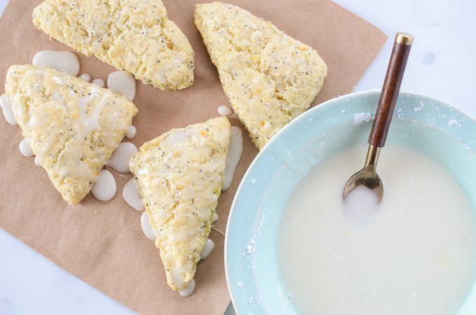Overhead view of Meyer Lemon Poppyseed Scones with a bowl of icing.