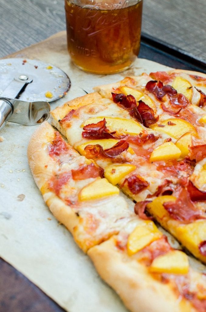 Peach prosciutto pizza sliced and with a glass of tea. 