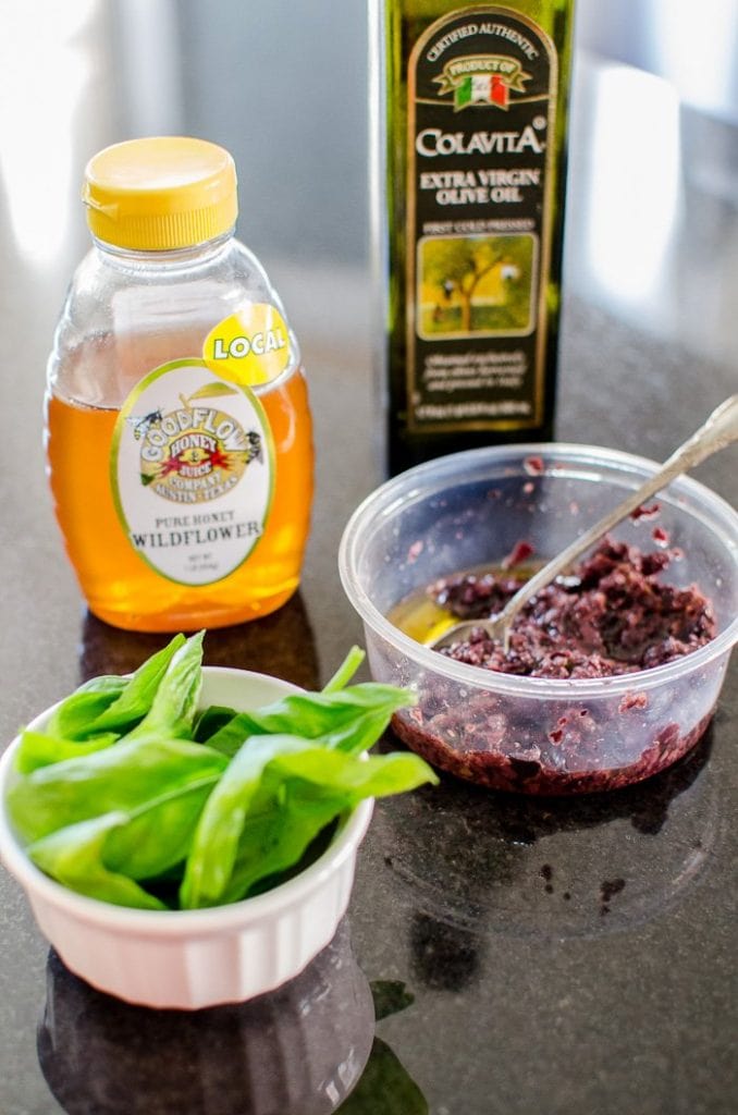Fresh finishing toppings for pizza including basil, honey, olive oil, and olives. 