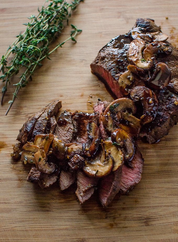 A sliced steak with mushrooms on top.