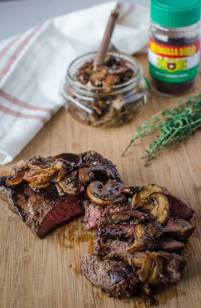 A sliced steak topped with mushrooms.