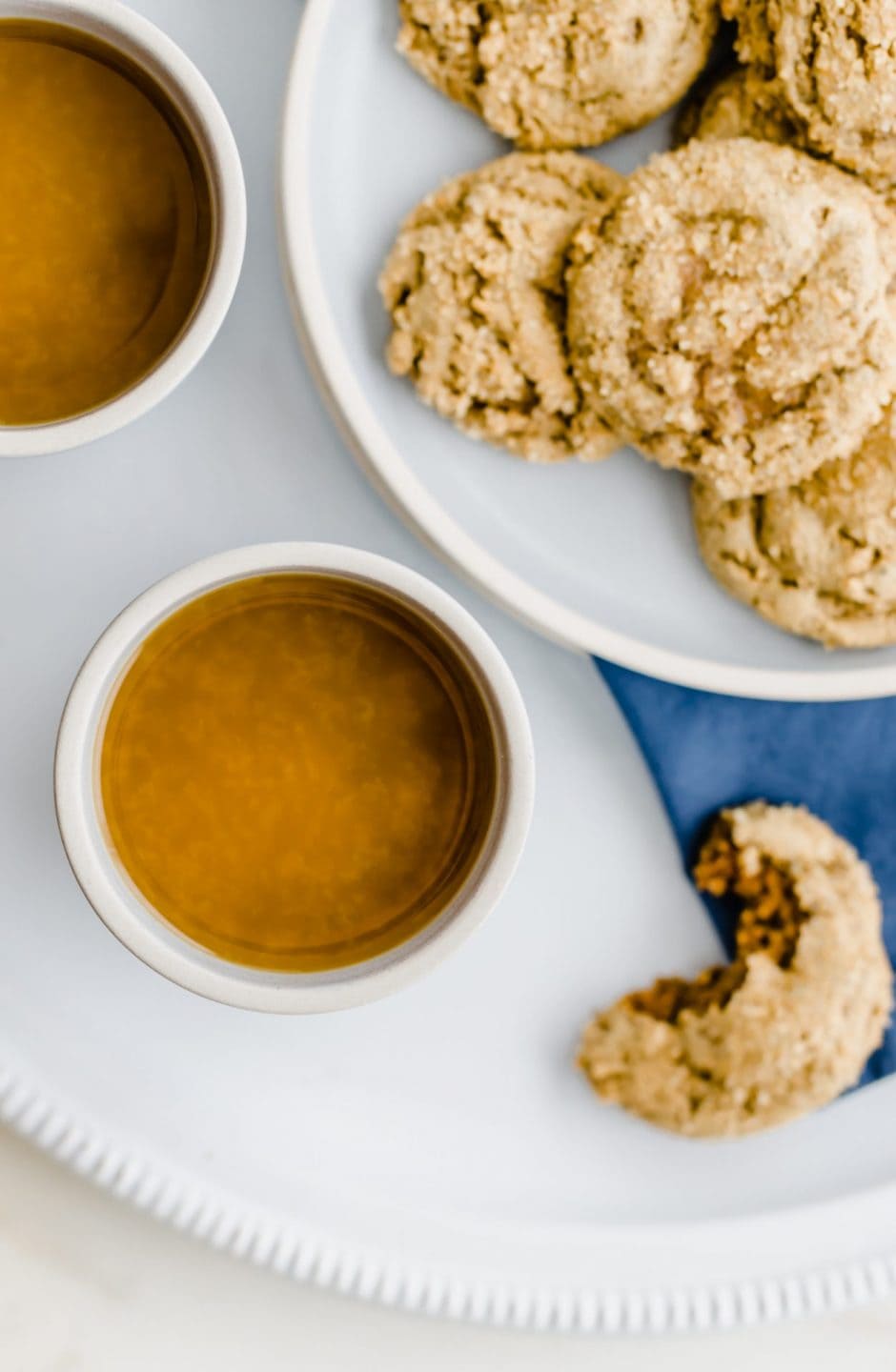 An overhead shot of a blue ceramic cup of spiced tea with a plate of ginger cookies on the side. 