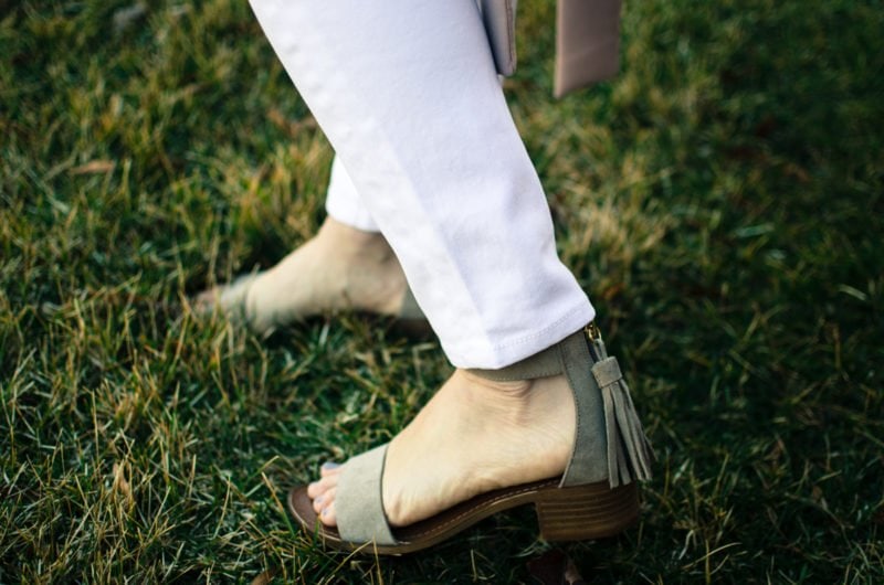 A chic spring look featuring a neutral color palette of a blush trench coat, white blouse, white jeans, and taupe sandals. Style and fashion inspiration for women.