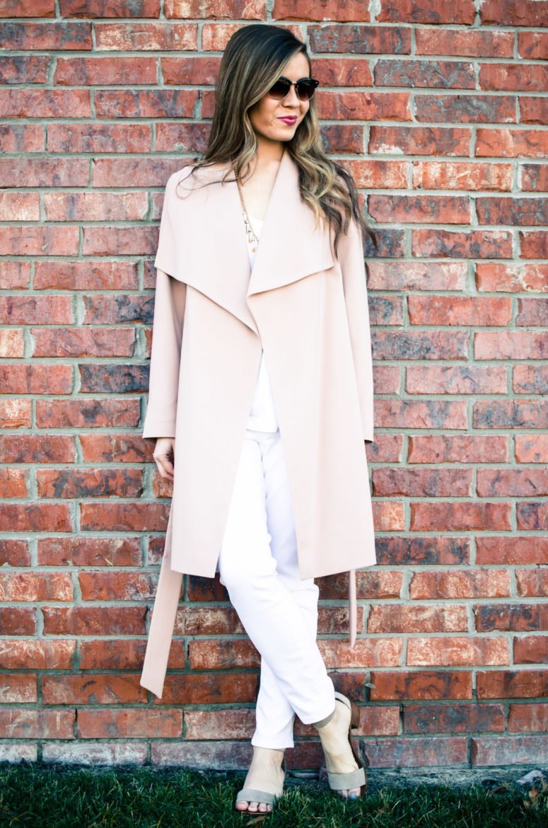 A chic spring look featuring a neutral color palette of a blush trench coat, white blouse, white jeans, and taupe sandals. Style and fashion inspiration for women.