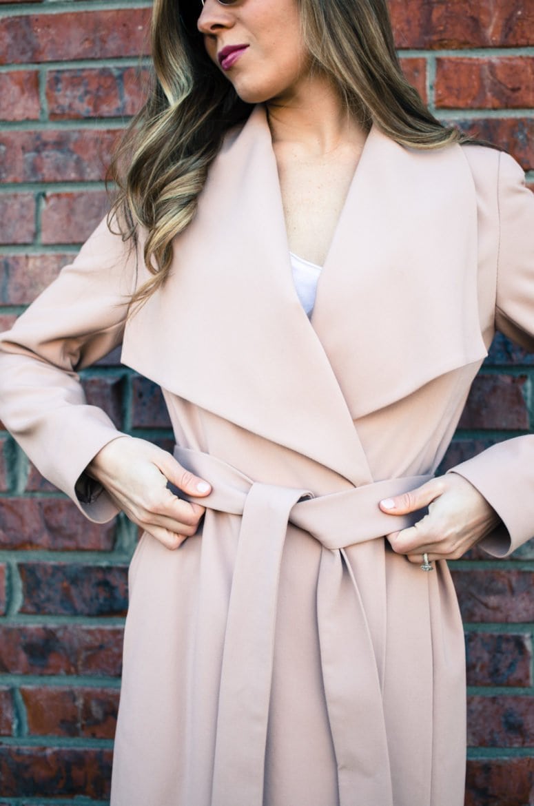 A chic spring look featuring a neutral color palette of a blush trench coat, white blouse, white jeans, and taupe sandals. Style and fashion inspiration for women.