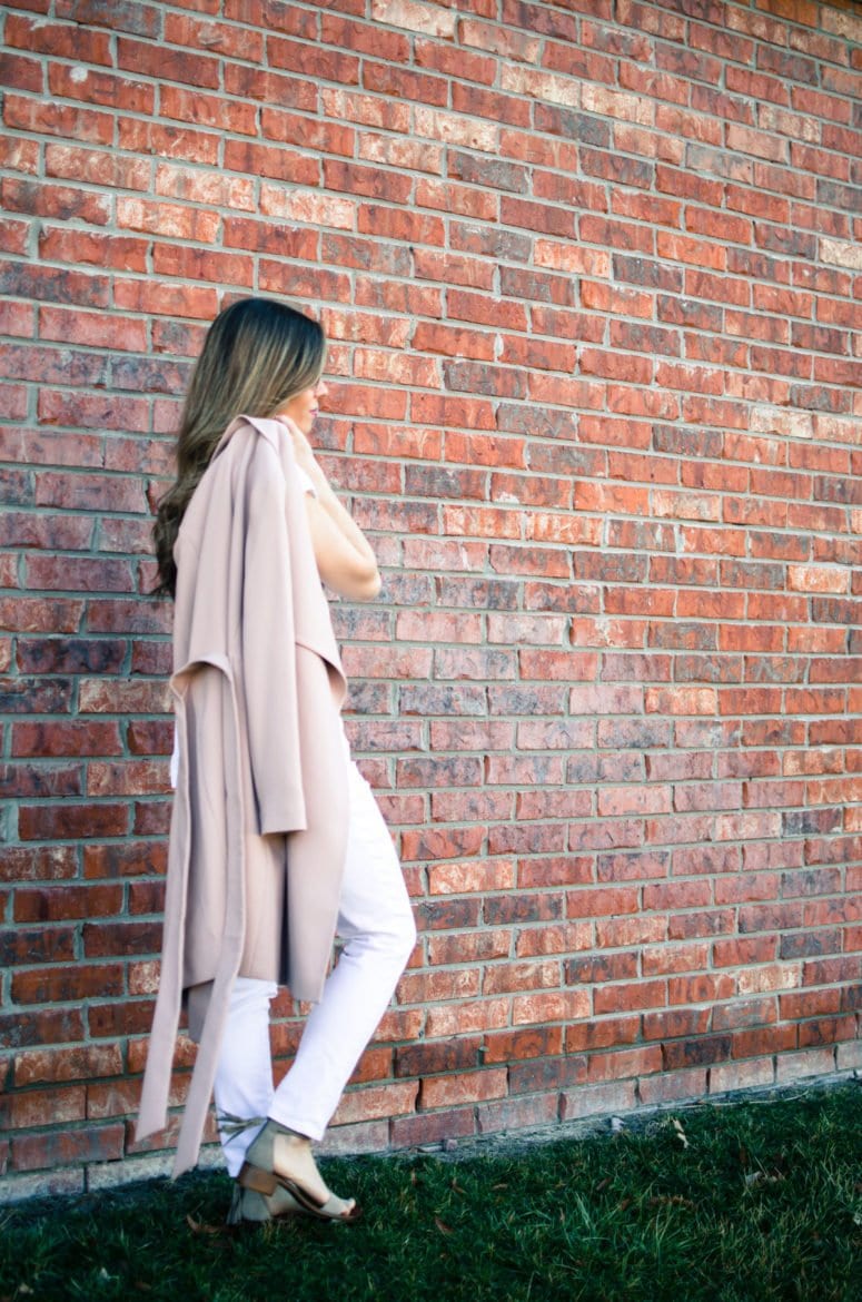 A chic spring look featuring a neutral color palette of a blush trench coat, white blouse, white jeans, and taupe sandals. Style and fashion inspiration for women.