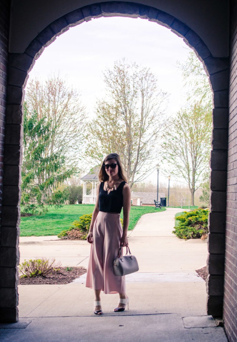 Blush pink culottes paired with a cropped black shell and Sam Edelman heels with a nude bag and necklace. Elegant spring outfit idea!