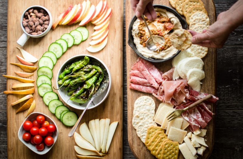 A cutting board with charcuterie and vegetables.