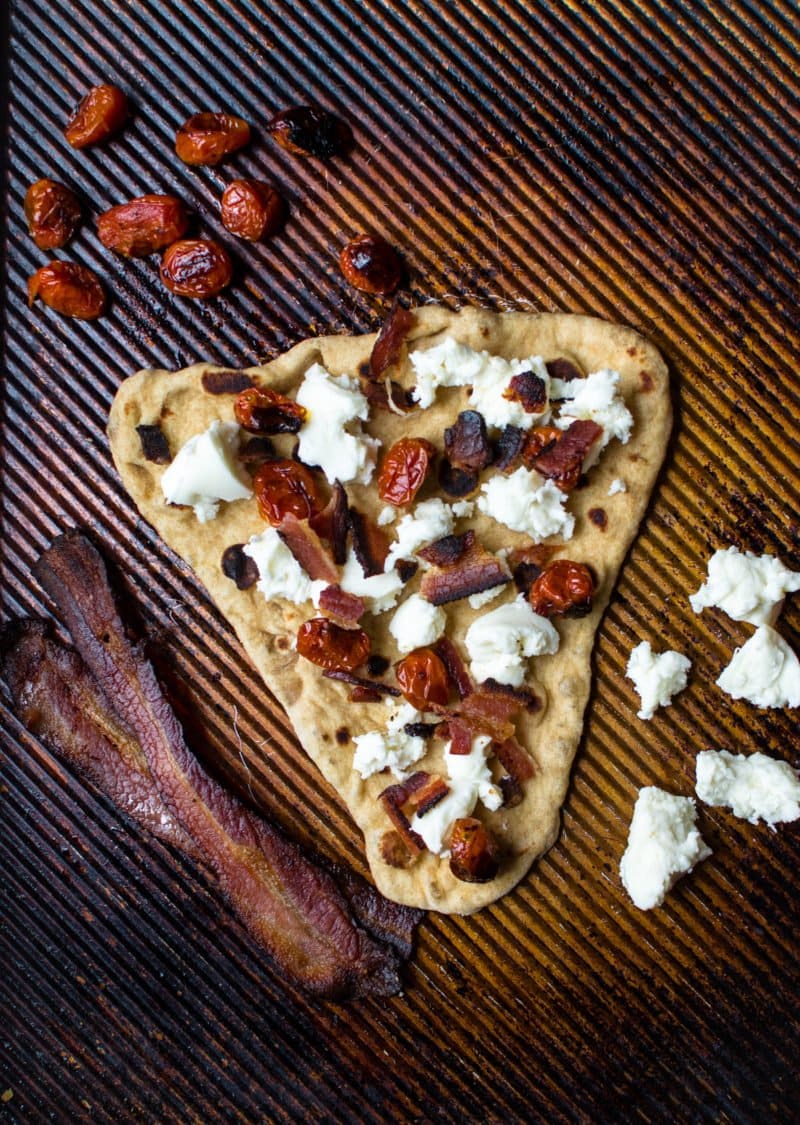 A slice of pizza on a pan with toppings.