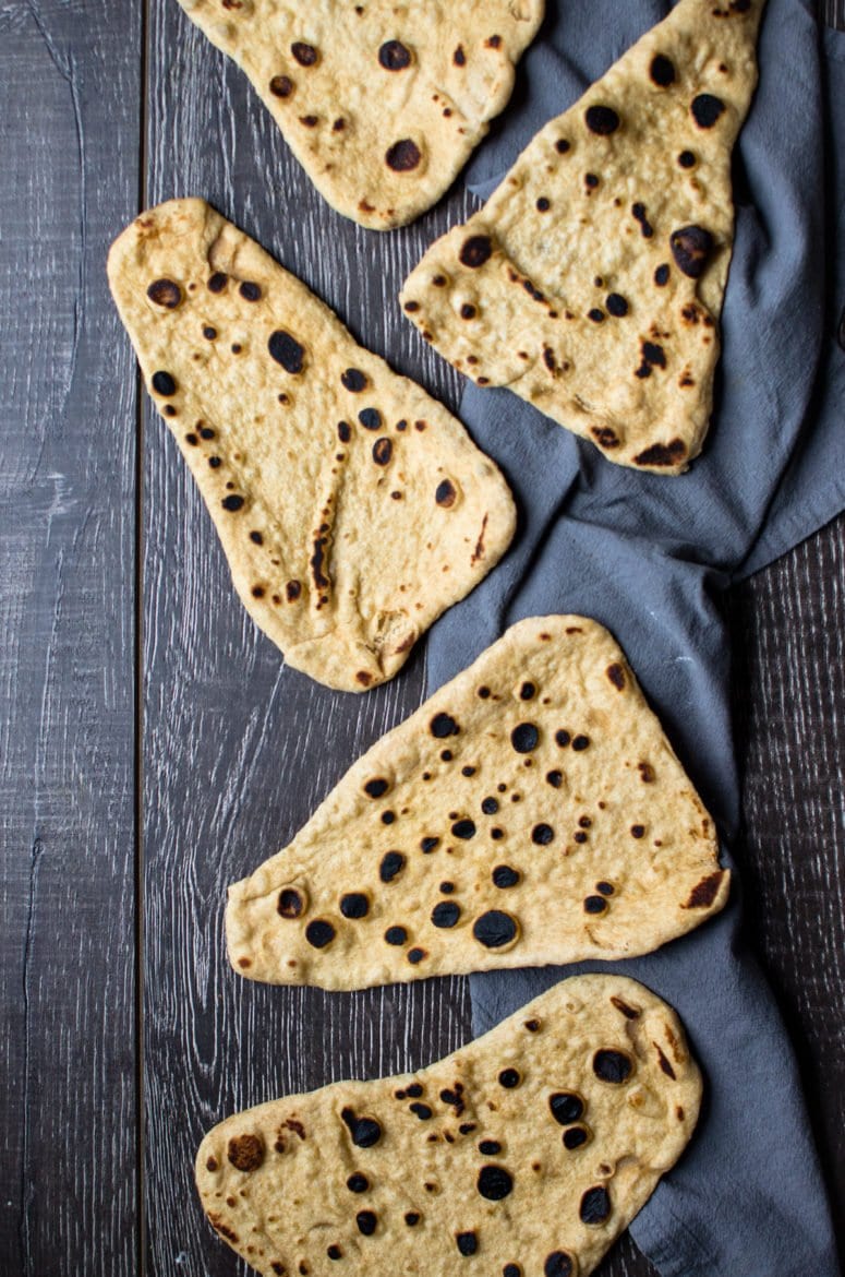 Naan bread spread out on a wood table. 