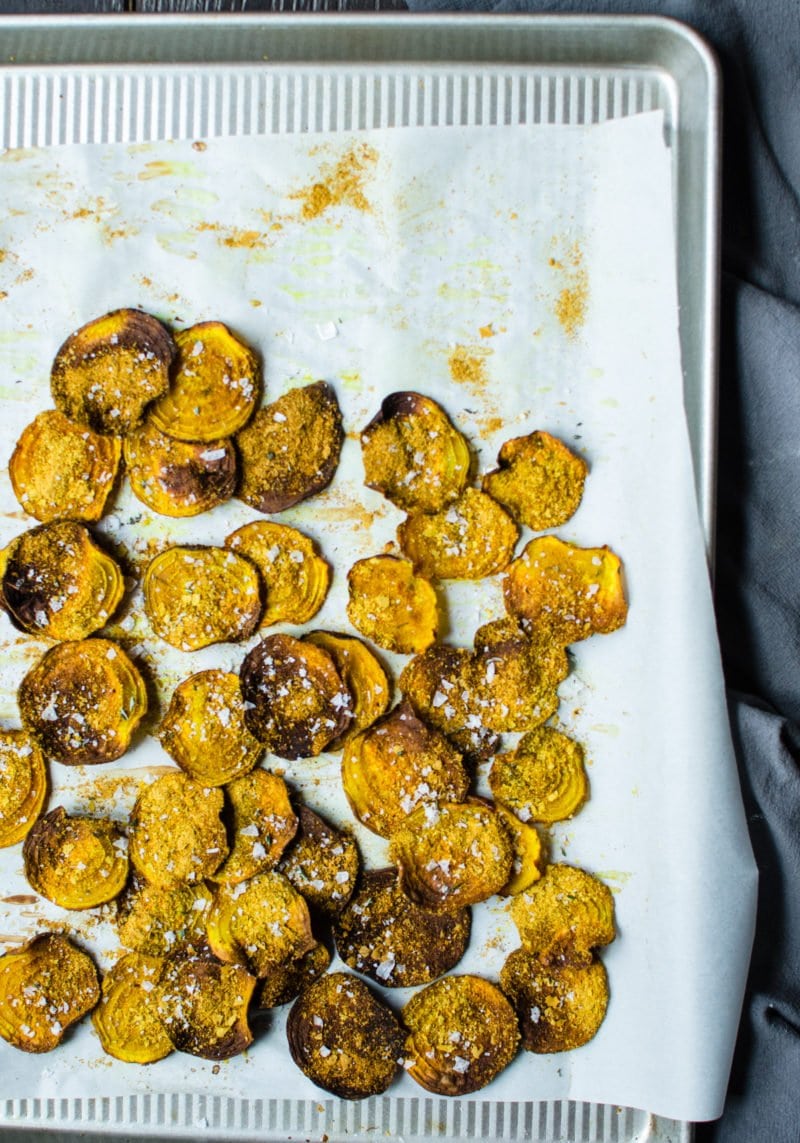 Crispy beet chips with cheese seasoning and salt on a baking sheet. 