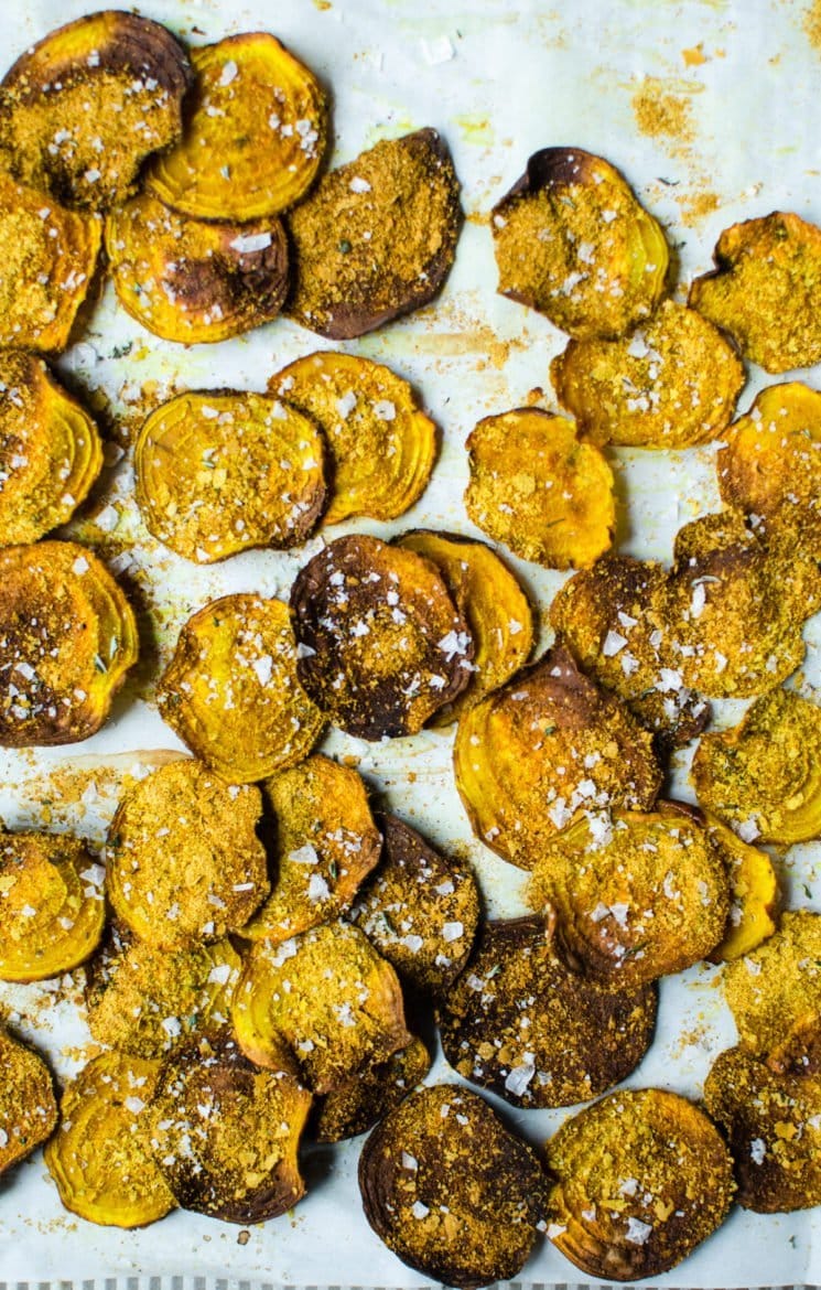 Cheesy beet chips on a baking sheet with sea salt. 