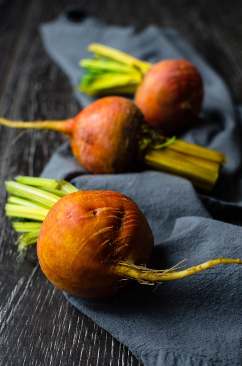 Three golden beets on a blue dish towel.