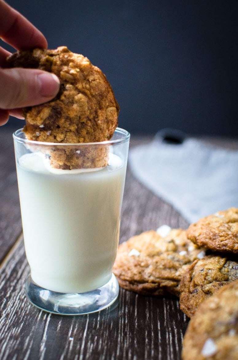 Chocolate chip cookie being dipped in milk. 