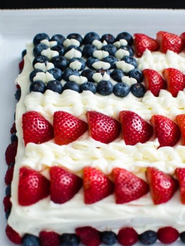 This fresh berry flag cake is made from scratch and is moist, flavorful, and perfect to serve for the 4th of July or Memorial Day! It's decorated with loads of berries and cream cheese frosting!