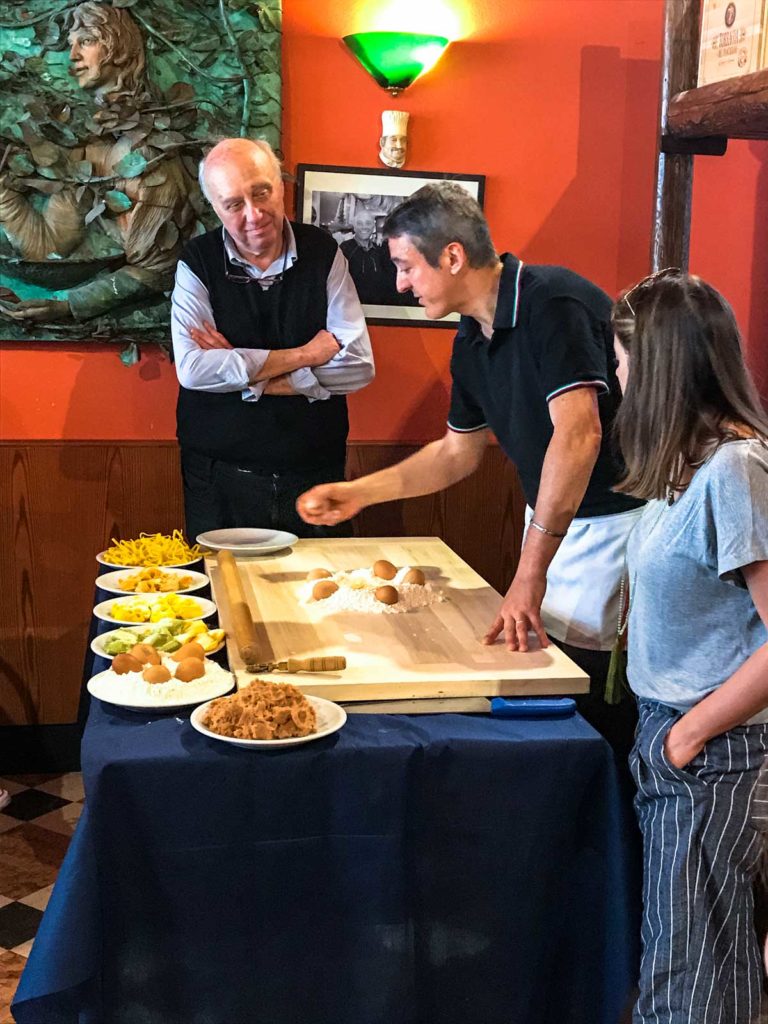 A chef demonstrating how to make fresh tortellini in a cooking class. 