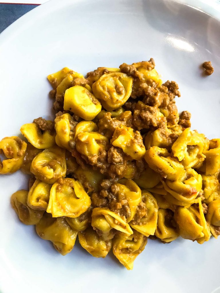 A plate of fresh tortellini with meat sauce. 