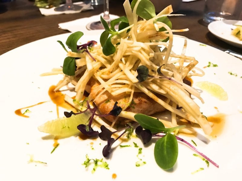 A chicken dish with microgreens on top. 