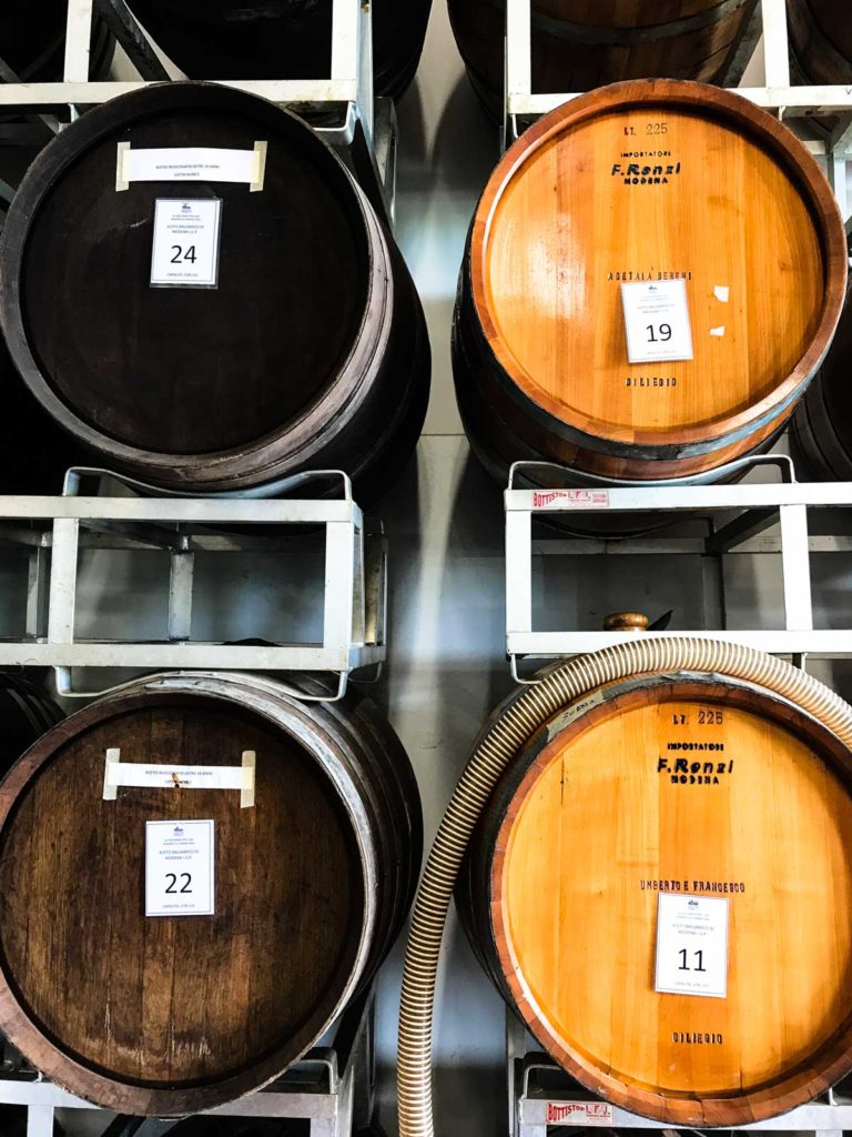 Two types of wood barrels on a shelf for aging balsamic vinegar. 