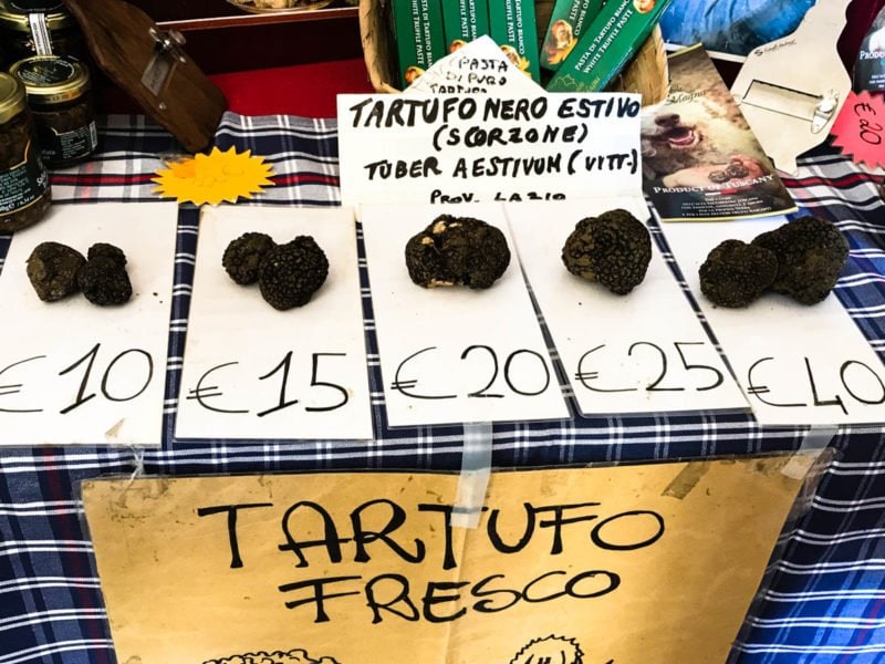 Fresh truffles lined up by size and weight on a market table.