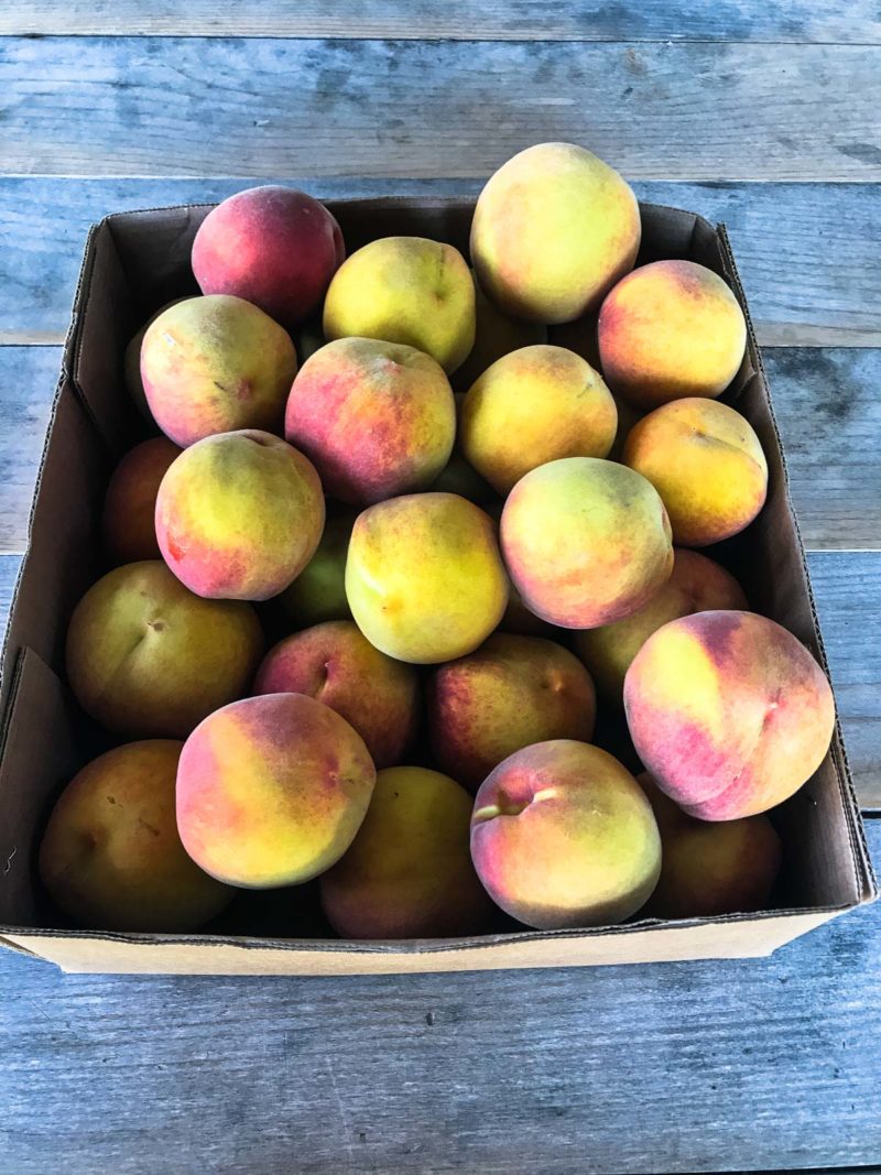 Box of peaches on a wooden table