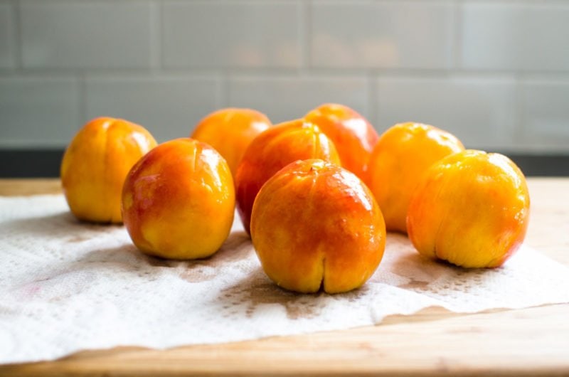 A row of fresh, blanched peaches with peels removed. 