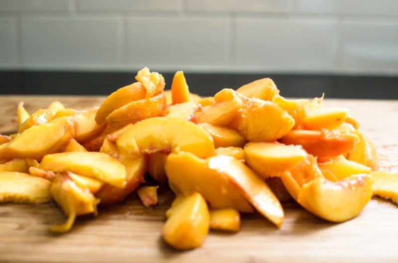 Sliced peaches on a wood cutting board. 