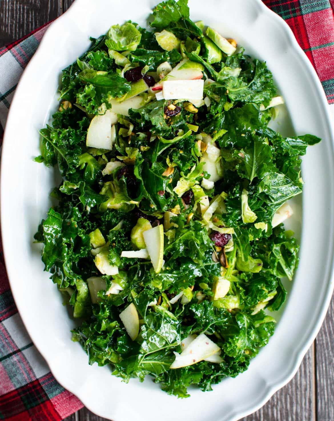 A mixed salad with apples and cranberries on a white platter. 