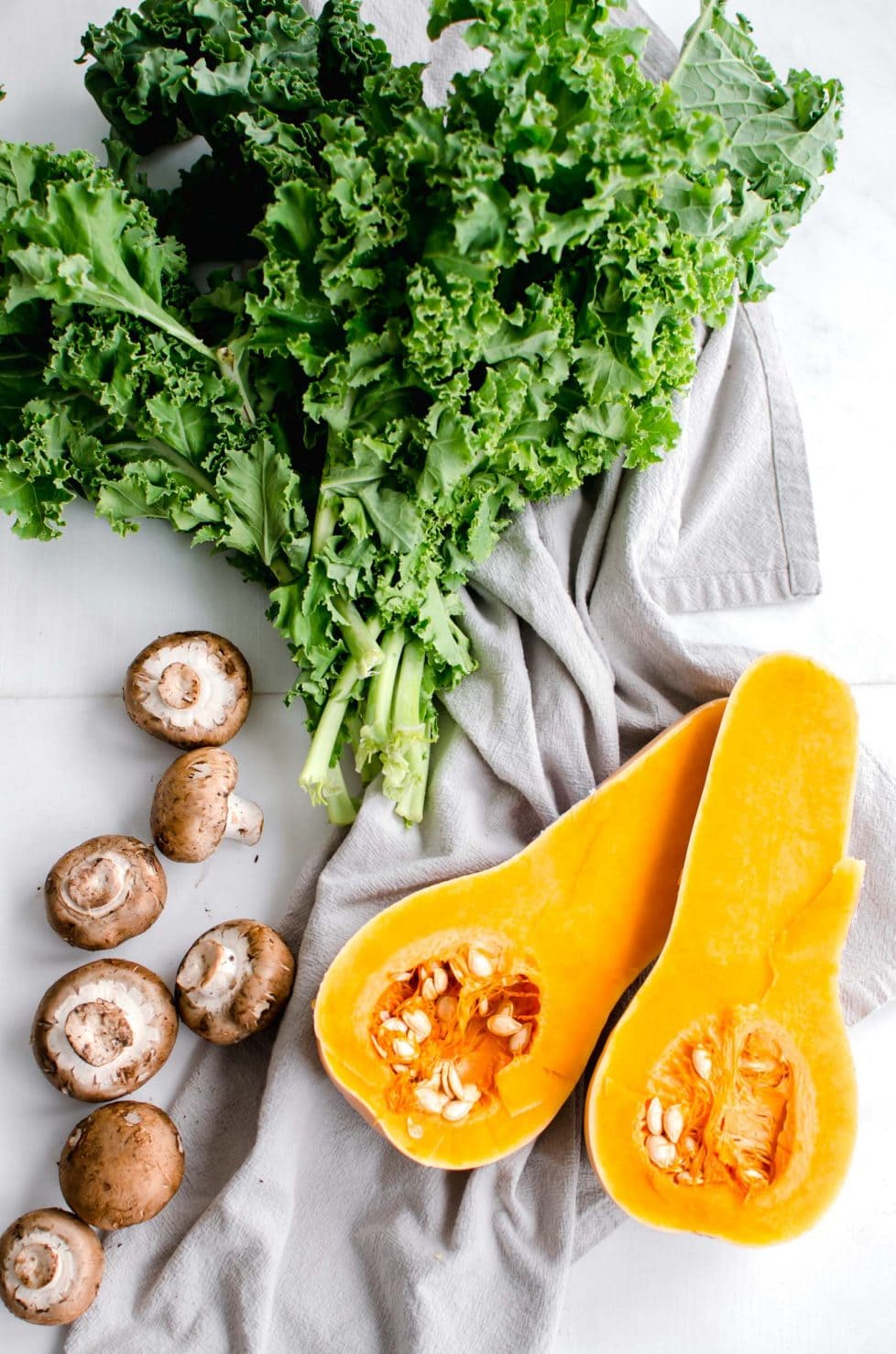 Kale, butternut squash, mushrooms on a cloth.