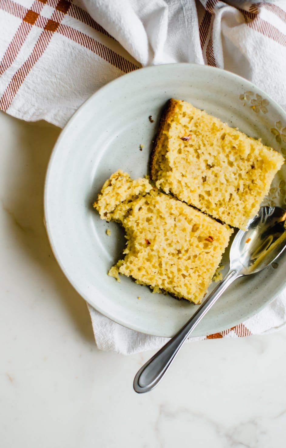 A sliced piece of cornbread on a plate.