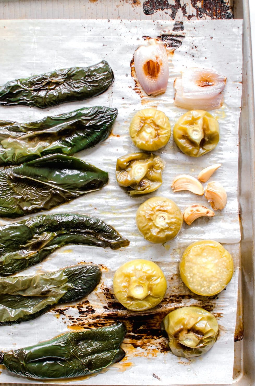 A cooking tray with roasted poblanos, garlic and tomatillos.