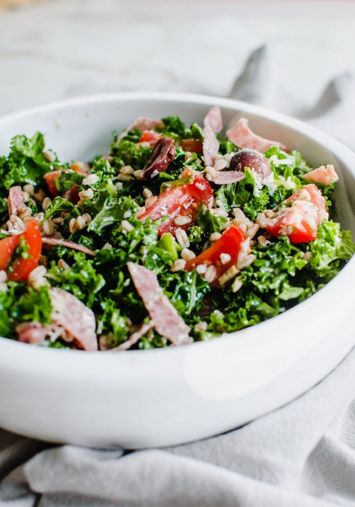 Overhead side photo of Italian kale salad in a white serving bowl.