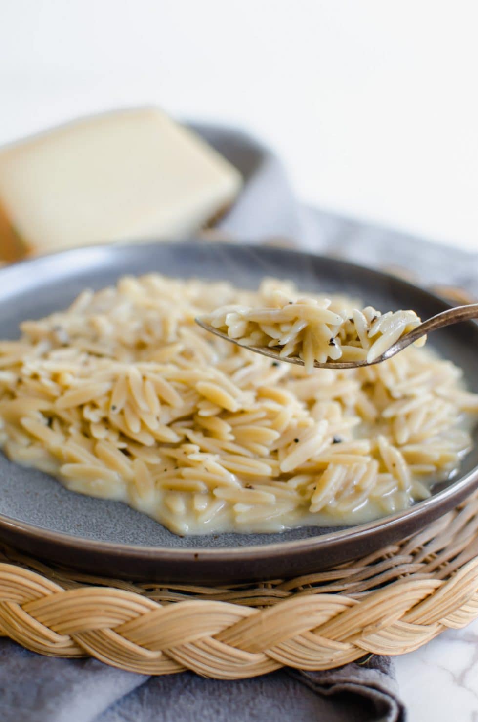 Photo of orzo pasta cacio y pepe on a blue plate.
