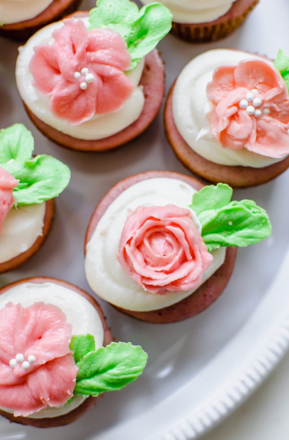 An overhead shot of a strawberry cupcake with cream cheese frosting that is topped with a pink buttercream rose. 