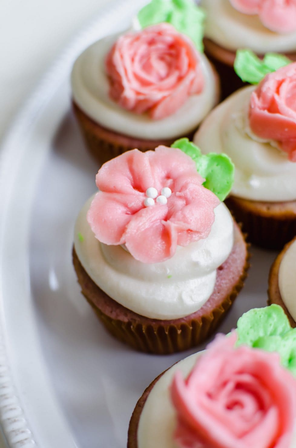 An overhead shot of a strawberry cupcake with cream cheese frosting and a pink buttercream flower. 