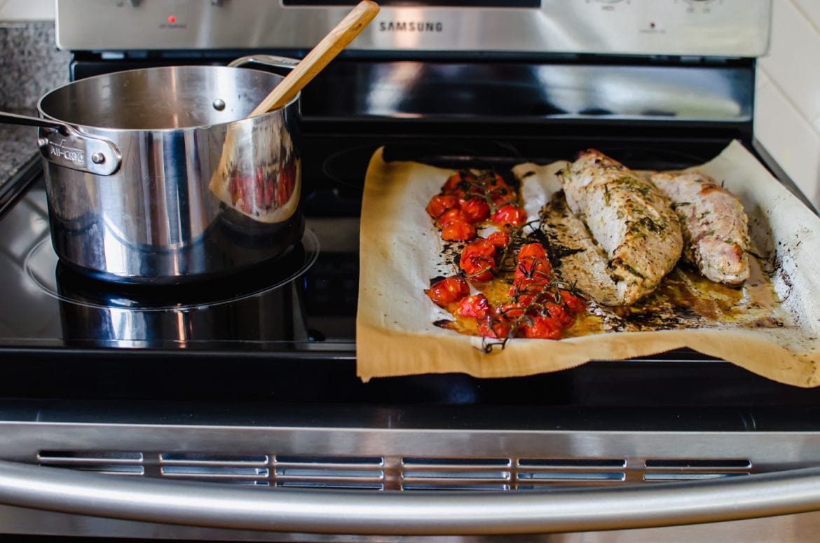 A stove with a pot and a sheet pan on top. 