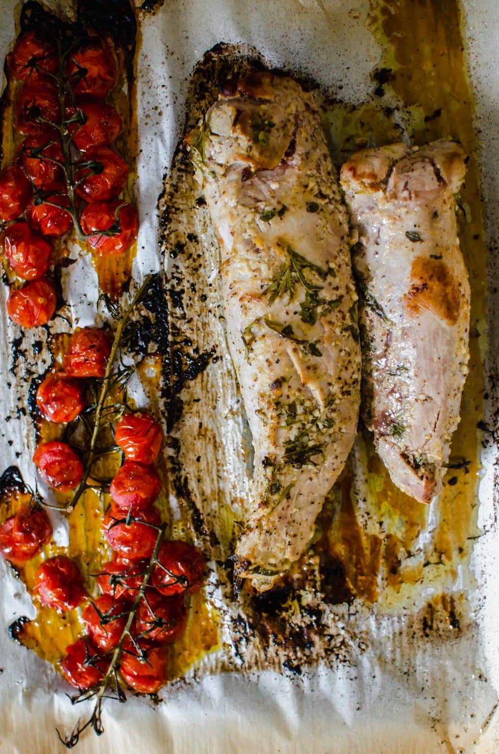 A sheet pan with pork and blistered tomatoes.