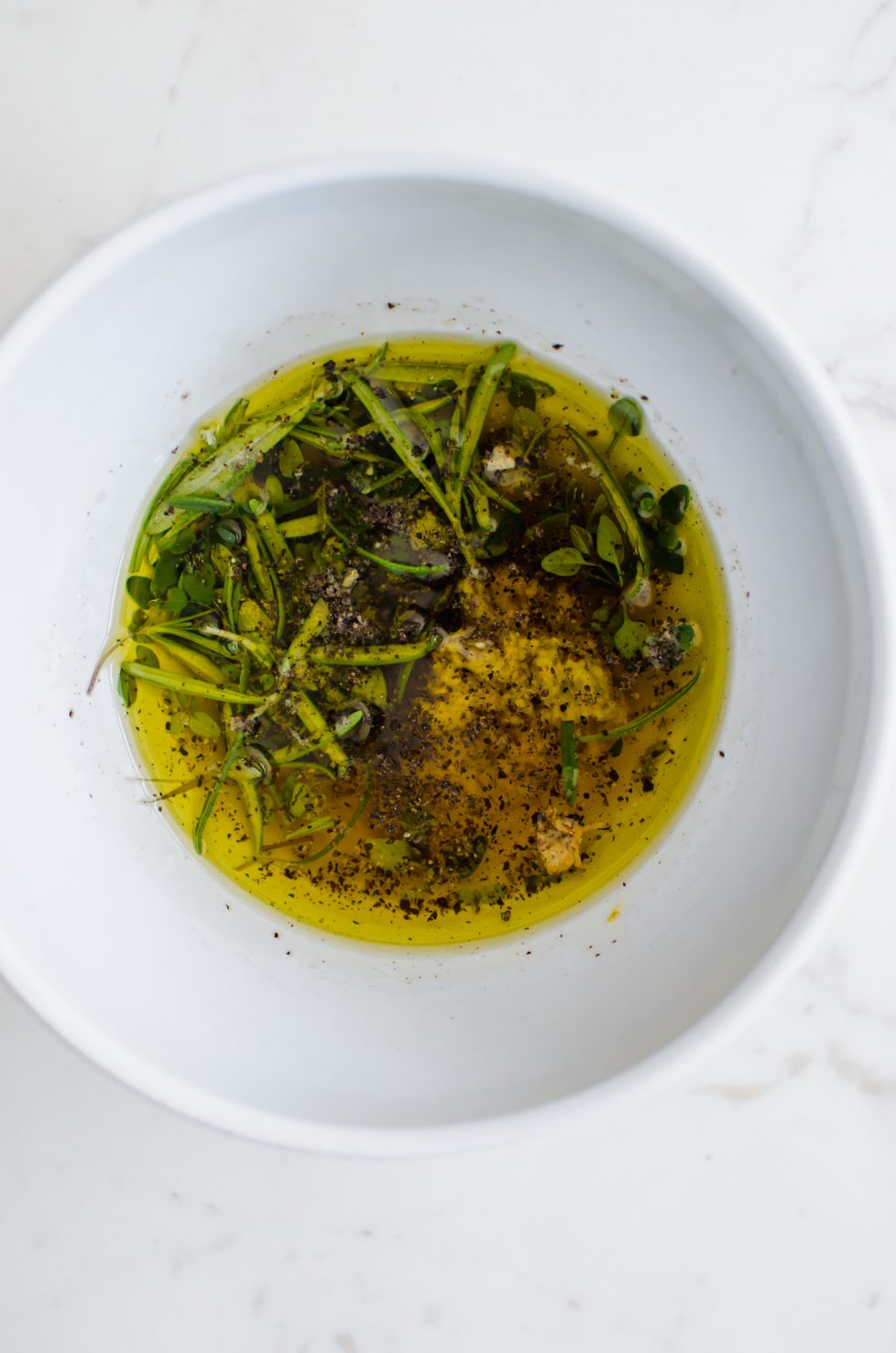 A bowl with olive oil and herbs.