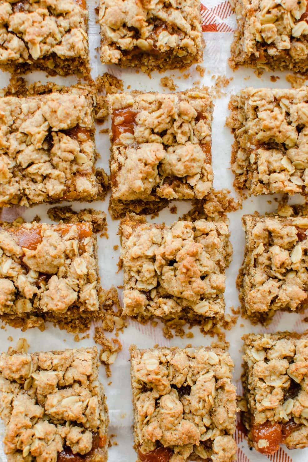 An overhead shot of Pecan Butter and Peach Jam Crumble Bars sitting on white parchment paper. 