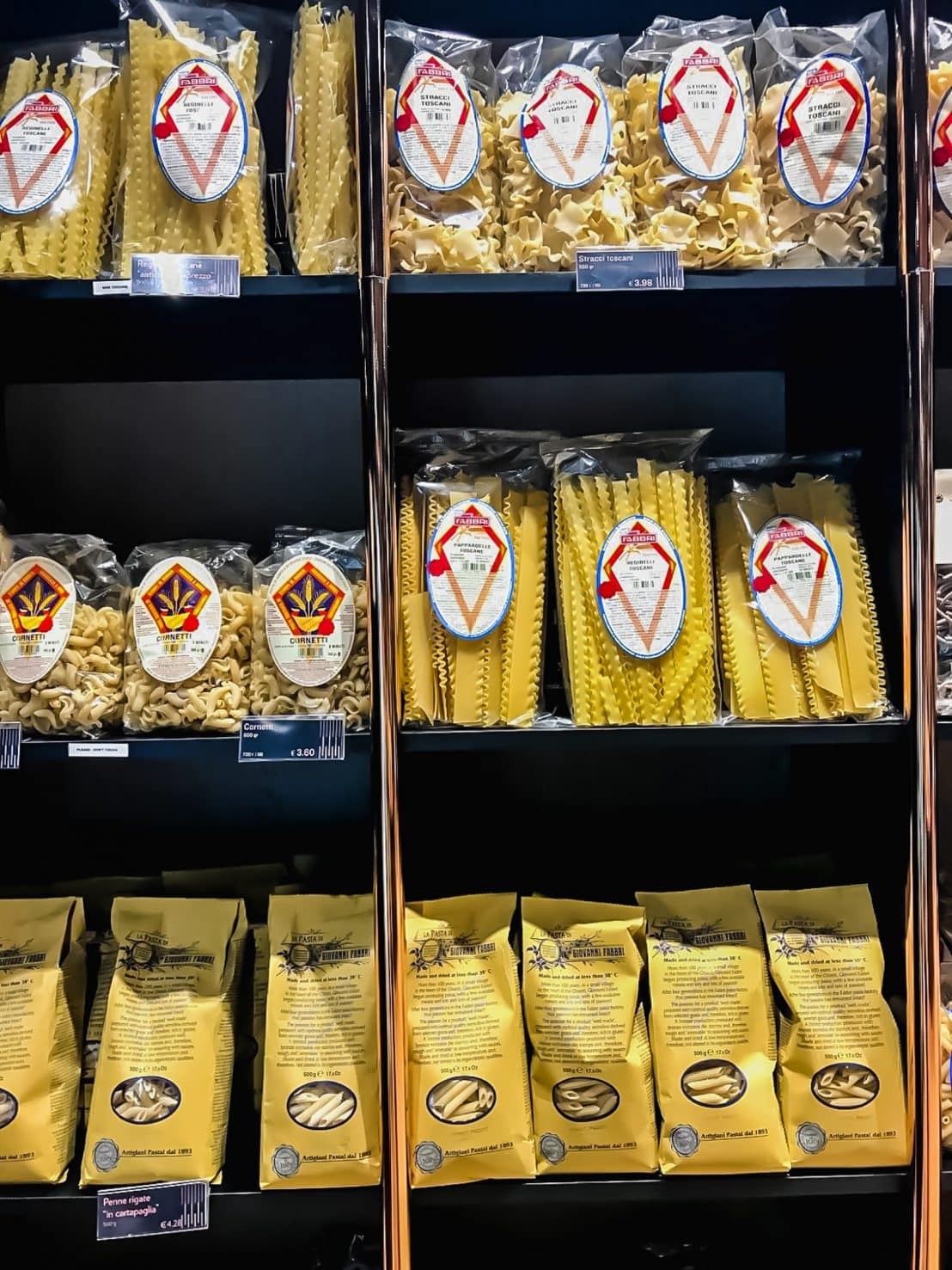 A photo of dried pasta packages on shelves in a store. 