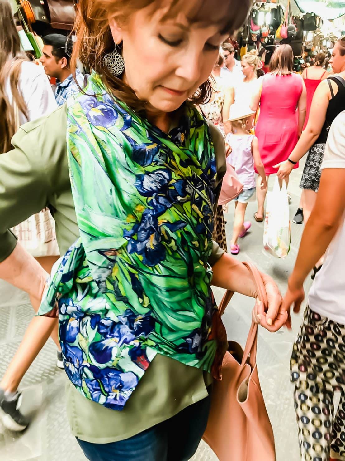 A woman trying on a silk scarf in the San Lorenzo market of Florence. 