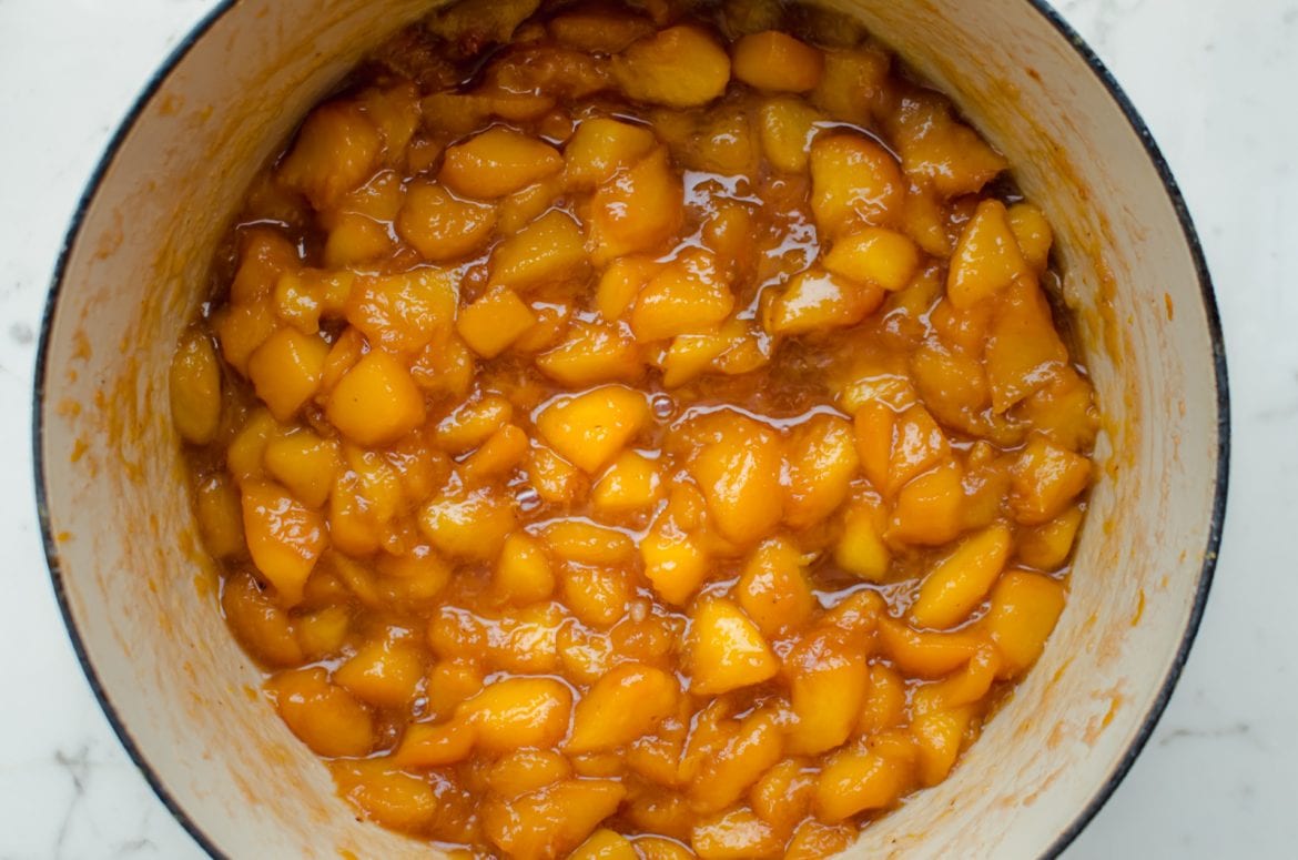 An overhead shot of peach jam cooking in a Dutch oven. 