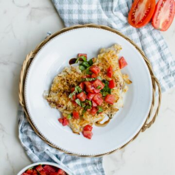 An overhead shot of a piece of bruschetta potato chip chicken on a white plate.